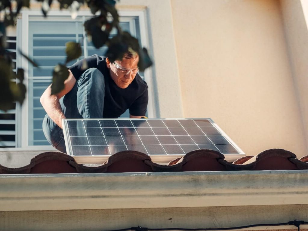 Mężczyzna instalujący panel słoneczny, promujący zrównoważone i odnawialne źródła energii.