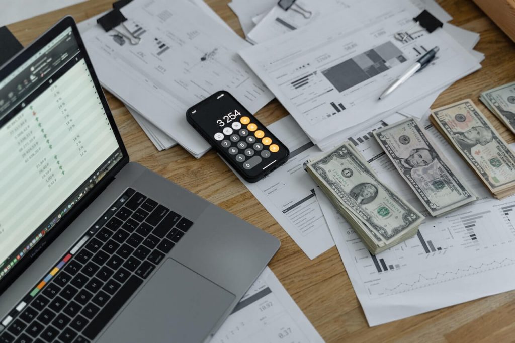 Rachunki i gotówka na stole, symbolizujące zarządzanie finansami i wydatki w obecności komputera.