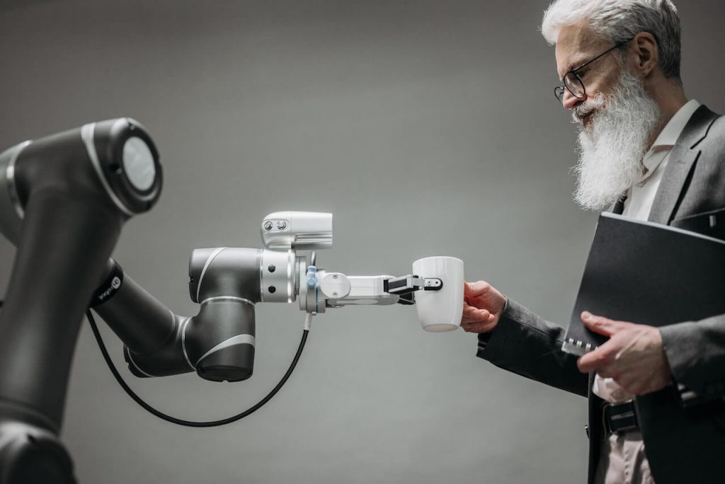Robotyczne ramię podające mężczyźnie filiżankę kawy, prezentujące automatyzację i wygodę.